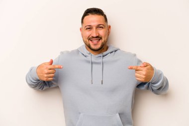 Beyaz arka planda izole edilmiş genç bir İspanyol. Parmakları aşağıda, olumlu hisler içinde..