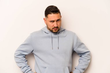 Beyaz arka planda izole edilmiş, hoşnutsuzca kaşlarını çatmış, kollarını kavuşturmuş genç bir İspanyol..