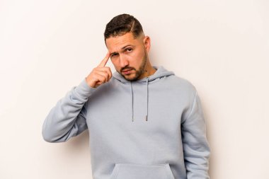 Beyaz arka planda izole edilmiş genç İspanyol bir adam şakağı parmağıyla işaret ediyor, düşünüyor ve bir göreve odaklanıyor..