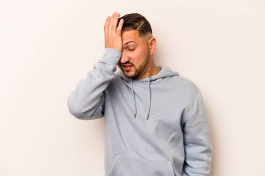 Beyaz arka planda izole edilmiş genç İspanyol bir adam bir şeyi unutuyor. Alnına avuç içi ile vuruyor ve gözlerini kapıyor..