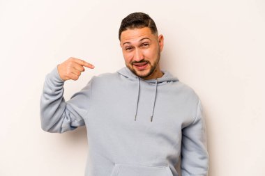 Beyaz arka planda izole edilmiş genç bir İspanyol gömlek fotokopi alanını elle işaret ediyor, gururlu ve kendinden emin.