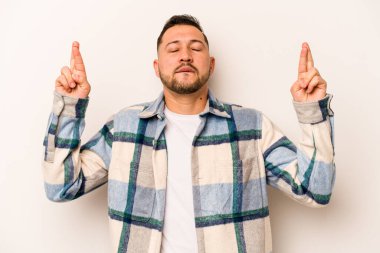 Latin kökenli genç bir adam beyaz arka planda izole edilmiş şans dilemek için şans diliyor.