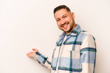 Beyaz arka planda izole edilmiş genç bir İspanyol hoş geldin ifadesi sergiliyor..