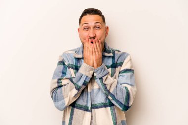 Beyaz arka planda izole edilmiş genç İspanyol adam elleriyle ağzını kapatırken şok oldu..