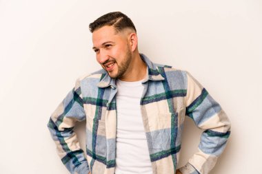 Beyaz arka planda izole edilmiş genç İspanyol bir adam. Kendine güveniyor. Kalçaları tutuyor..