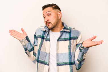 Beyaz arka planda izole edilmiş genç İspanyol bir adam. Kafası karışmış ve omuz silkiyor. Kopya alanını tutmak için..