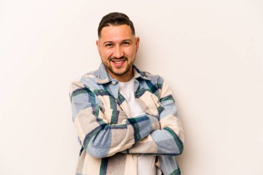 Beyaz arka planda kendini güvende hisseden, kararlılıkla kollarını kavuşturan genç İspanyol bir adam..