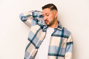 Beyaz arka planda izole edilmiş genç bir İspanyol. Çok yorgun ve uykulu. Elini başının üstünde tutuyor..