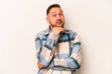 Beyaz arka planda izole edilmiş genç bir İspanyol şüpheli, belirsiz, seni muayene ediyor..