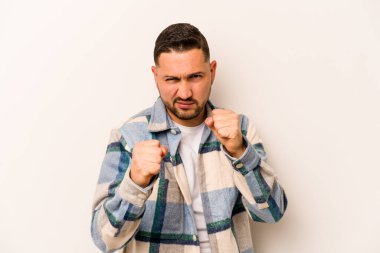 Beyaz arka planda izole edilmiş genç İspanyol adam kameraya yumruk gösteriyor, agresif yüz ifadesi..