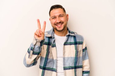 Beyaz arka planda izole edilmiş genç İspanyol adam iki numarayı parmaklarıyla gösteriyor..