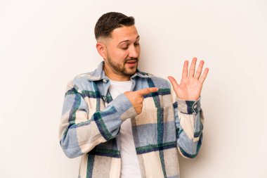 Beyaz arka planda izole edilmiş genç İspanyol adam gülümseyerek beş numarayı parmaklarıyla gösteriyor..