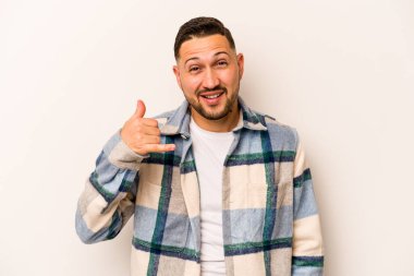 Beyaz arka planda izole edilmiş genç İspanyol bir adam bir şeye gülüyor, elleriyle ağzını kapatıyor..