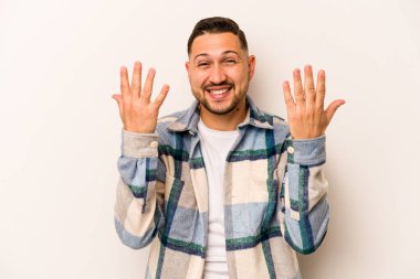 Beyaz arka planda izole edilmiş genç İspanyol adam on numarayı elleriyle gösteriyor..