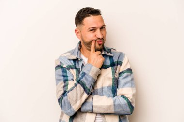 Beyaz arka planda izole edilmiş genç İspanyol adam alaycı bir ifadeyle kameraya bakıyor..