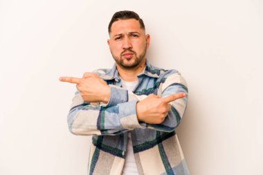 Beyaz arka plan noktalarında izole edilmiş genç İspanyol adam iki seçenek arasında seçim yapmaya çalışıyor..