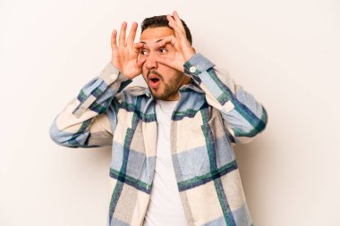 Beyaz arka planda izole edilmiş genç bir İspanyol başarılı bir fırsat yakalamak için gözlerini açık tutuyor..