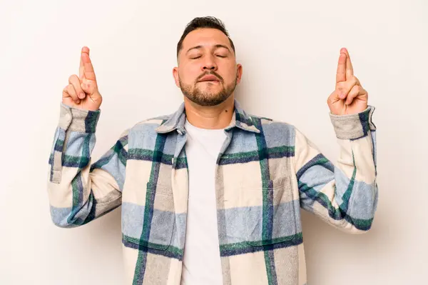 Latin kökenli genç bir adam beyaz arka planda izole edilmiş şans dilemek için şans diliyor.