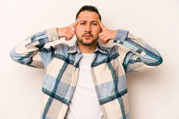 Beyaz arka planda izole edilmiş genç İspanyol bir adam bir göreve odaklanmış, işaret parmaklarını işaret ediyor..