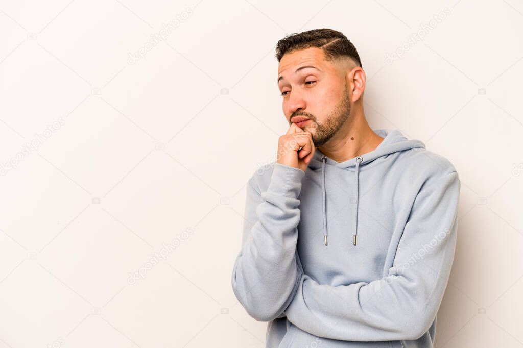 Young hispanic man isolated on white background relaxed thinking about something looking at a copy space.