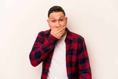 Beyaz arka planda izole edilmiş genç İspanyol adam elleri endişeli bir şekilde ağzı örtüyor..