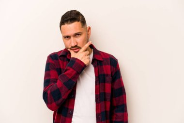 Latin kökenli genç bir adam beyaz arka planda izole edilmiş. Bir strateji planlıyor, bir iş yolu düşünüyor..