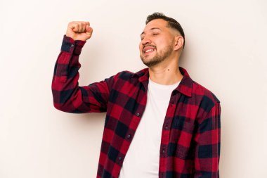 Beyaz arka planda izole edilmiş genç İspanyol bir adam zaferi, tutkuyu ve coşkuyu kutluyor, mutlu bir ifade..