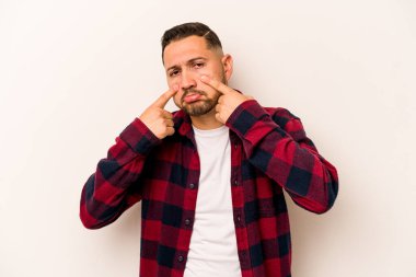 Beyaz arka planda izole edilmiş genç İspanyol bir adam ağlıyor, bir şeyden memnun değil, acı ve kafa karışıklığı konsepti..