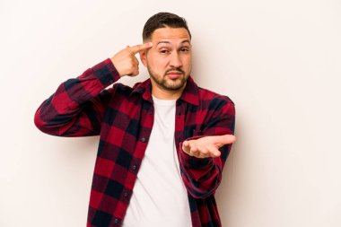 Latin kökenli genç bir adam beyaz arka planda izole edilmiş ve elinde bir ürün tutuyor..