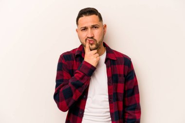 Genç İspanyol bir adam beyaz arka planda izole edilmiş düşünüyor, bakıyor, yansıtıyor, düşünüyor, bir fantezi kuruyor..