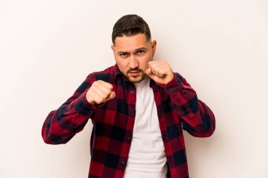 Latin kökenli genç bir adam beyaz arka planda izole edilmiş. Yumruk atıyor, sinirleniyor, kavga ediyor..