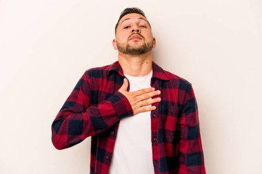 Genç İspanyol bir adam beyaz arka planda izole edilmiş yemin ediyor, elini göğsüne koyuyor..