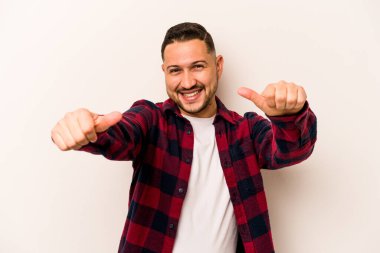 Beyaz arka planda izole edilmiş genç bir İspanyol. Baş parmağını kaldırıyor, gülümsüyor ve kendinden emin..