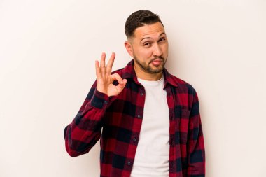 Beyaz arka planda izole edilmiş genç İspanyol bir adam bir göz kırptı ve elleriyle iyi bir jest yaptı..