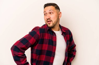 Beyaz arka planda soyutlanmış genç İspanyol adam gülümseyen, neşeli ve keyifli bir kenara bakıyor..