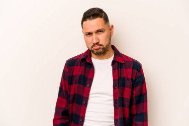 Genç İspanyol adam beyaz arka planda izole edilmiş üzgün, ciddi yüzlü, mutsuz ve hoşnutsuz..