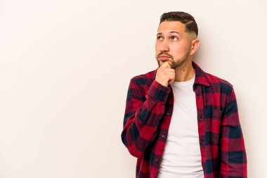 Beyaz arka planda izole edilmiş genç bir İspanyol şüpheli ve şüpheci bir ifadeyle yana bakıyor..