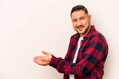 Beyaz arka planda izole edilmiş genç İspanyol bir adam avucunun içinde bir kopyasını tutuyor..