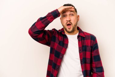Beyaz arka planda izole edilmiş genç İspanyol adam uzaklara bakıyor ve elini alnına koyuyor..