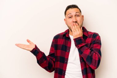 Beyaz arka planda izole edilmiş genç İspanyol adam, avuç içinde kopya alanı tutmaktan etkilenmiş..