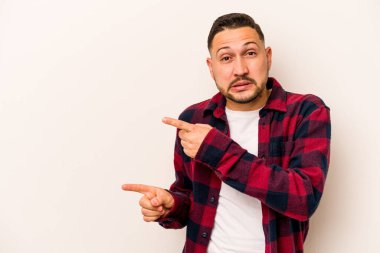 Beyaz arka planda izole edilmiş genç İspanyol adam işaret parmağıyla fotokopi alanını işaret ederek şok oldu..