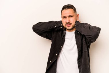 Genç İspanyol bir adam beyaz arka planda izole edilmiş kafasının arkasına dokunuyor, düşünüyor ve bir seçim yapıyor..