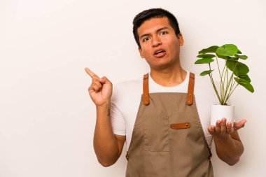 Genç bahçıvan, beyaz arka planda izole edilmiş bir bitki tutuyor.