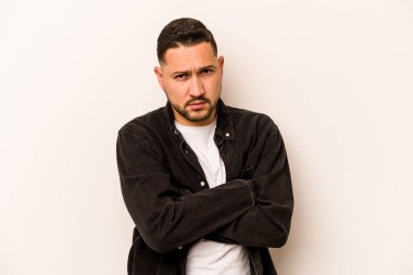 Beyaz arka planda izole edilmiş, hoşnutsuzca kaşlarını çatmış, kollarını kavuşturmuş genç bir İspanyol..