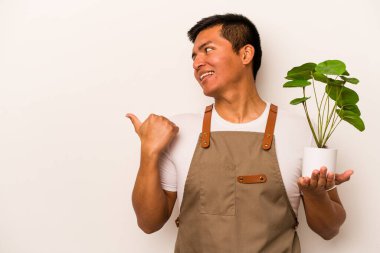 Genç bahçıvan İspanyol bir bitki tutuyor. Beyaz arka planda izole edilmiş. Baş parmak uzakta, gülen ve kaygısız..