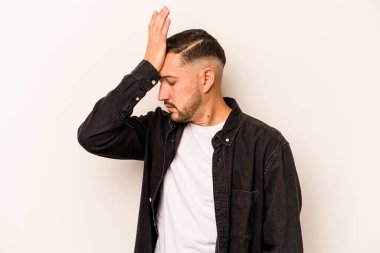 Beyaz arka planda izole edilmiş genç İspanyol bir adam bir şeyi unutuyor. Alnına avuç içi ile vuruyor ve gözlerini kapıyor..