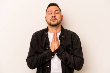 Beyaz arka planda izole edilmiş genç bir İspanyol. El ele tutuşup dua ediyor. Kendine güveniyor..
