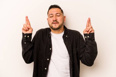 Latin kökenli genç bir adam beyaz arka planda izole edilmiş şans dilemek için şans diliyor.