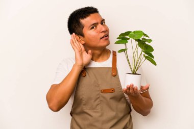 Genç bahçıvan İspanyol bir bitki tutuyor. Beyaz arka planda izole edilmiş. Dedikoduları dinlemeye çalışıyor..