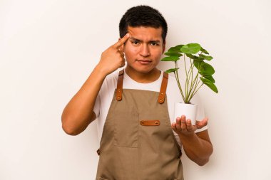 Genç bahçıvan İspanyol bir adam beyaz arka planda izole edilmiş bir bitki tutuyor işaret parmağıyla yaptığı hayal kırıklığı jestini gösteriyor..